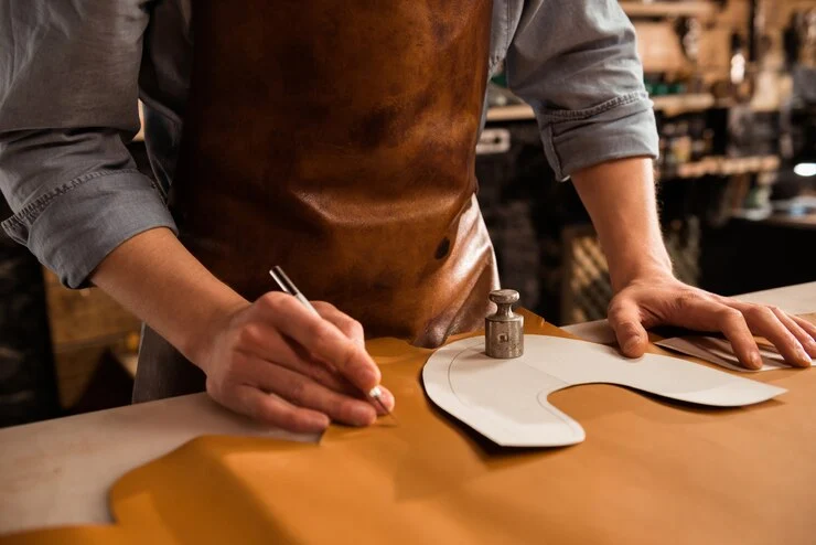 Artisan cutting leather while wearing a handmade leather apron